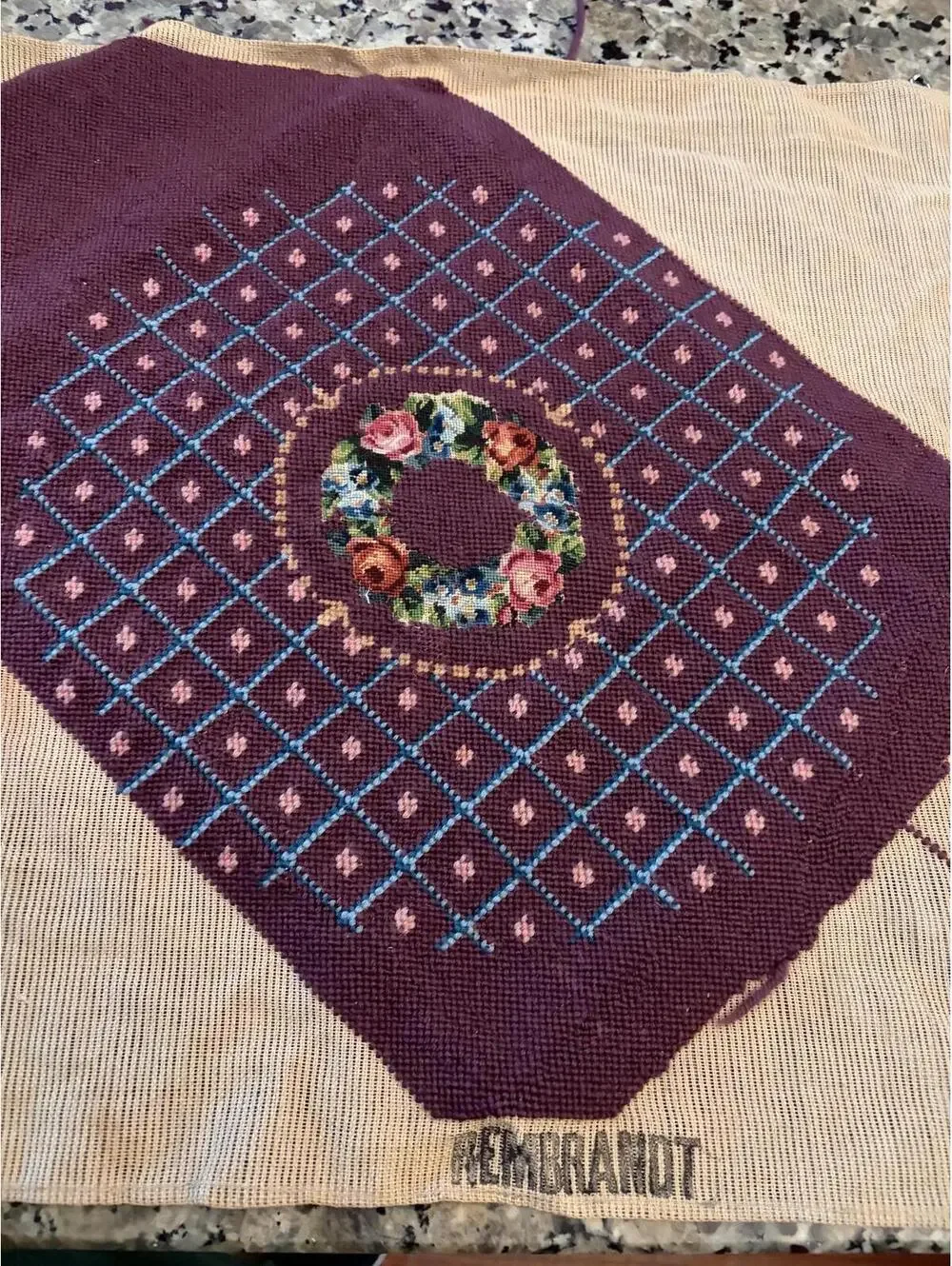 needlepoint tapestry featuring a wreath and geometric pattern.